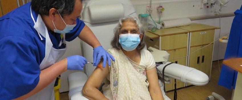 An elderly woman receives a vaccine dose