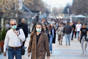 Man and woman walking in the the city center wearing protective masks stock photo