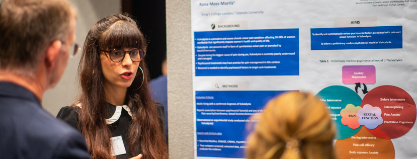 PhD student explaining her research poster to two people at event