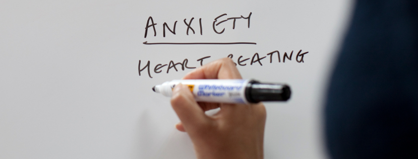 A hand writing 'Anxiety' on a whiteboard
