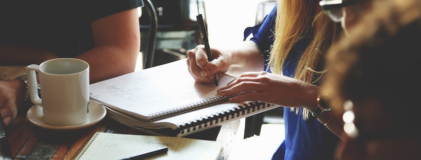 Person writing in notebook at table