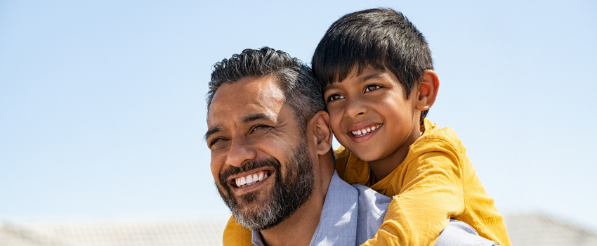 Father giving young son a piggyback looking happy