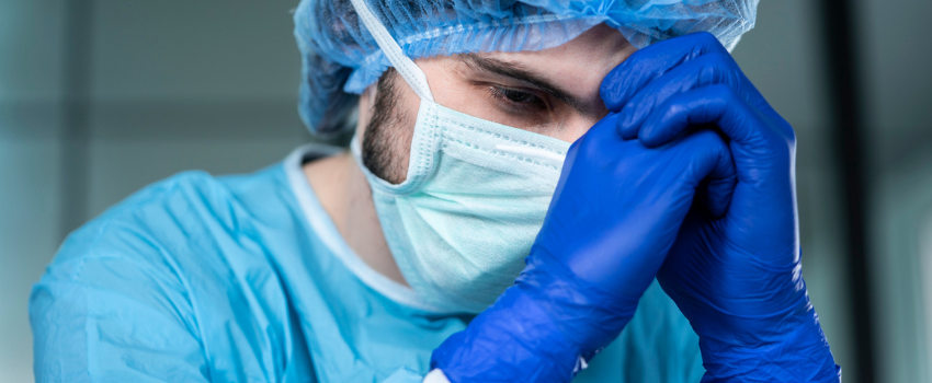 healthcare worker wearing mask holds head in hands