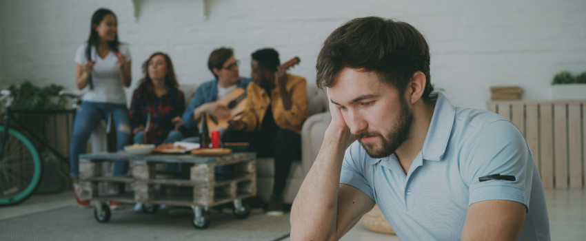 Person sits away from friends as they play the guitar