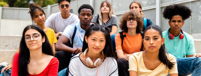 Group of multiracial teen high school students looking at camera sit on stairs outdoors