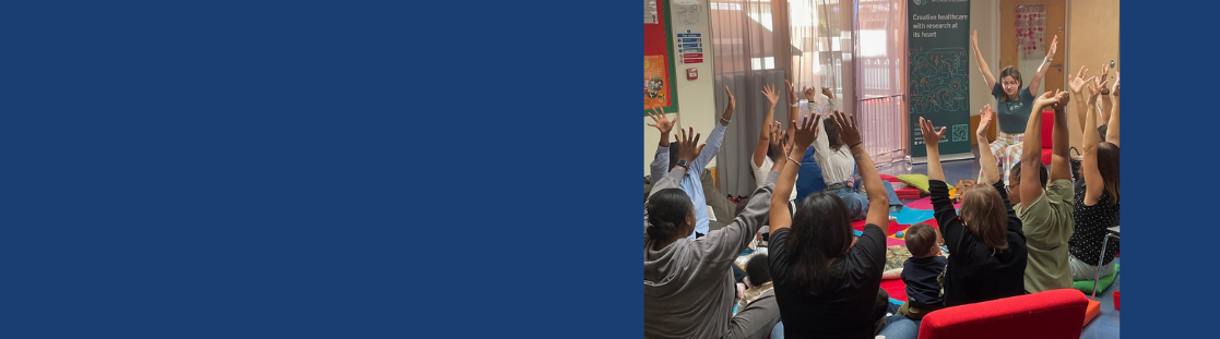 Women sitting in a group with babies with their hands up
