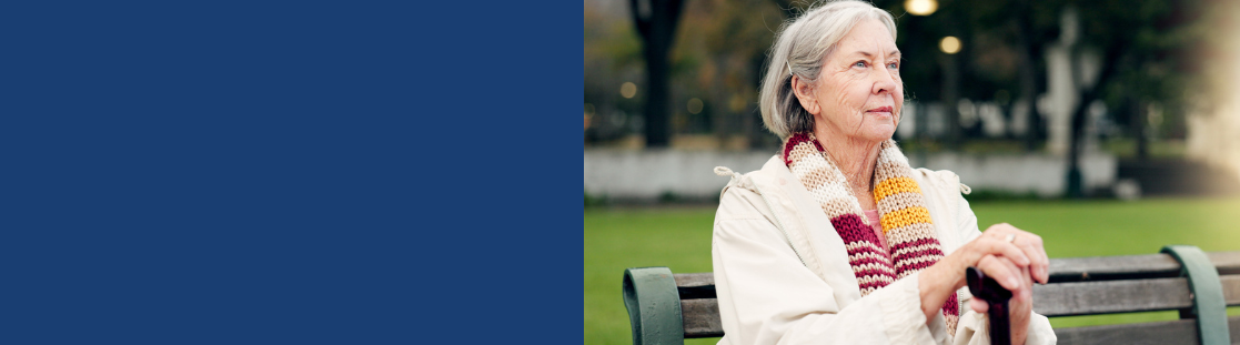 An older woman sat on a bench in a park