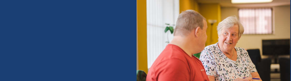 older woman speaks with man in community centre