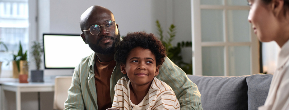 Portrait of smiling father and son listening to social worker in consultation on family relationship