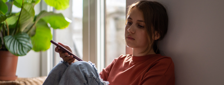 child looking sad holding smartphone