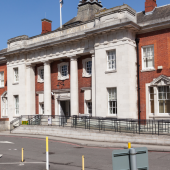 Historic red-brick building with white stone columns under a clear blue sky