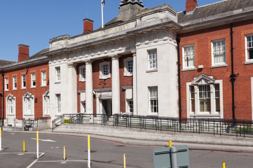 Historic red-brick building with white stone columns under a clear blue sky