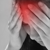 A woman in black and white experiencing a headache, which is glowing red
