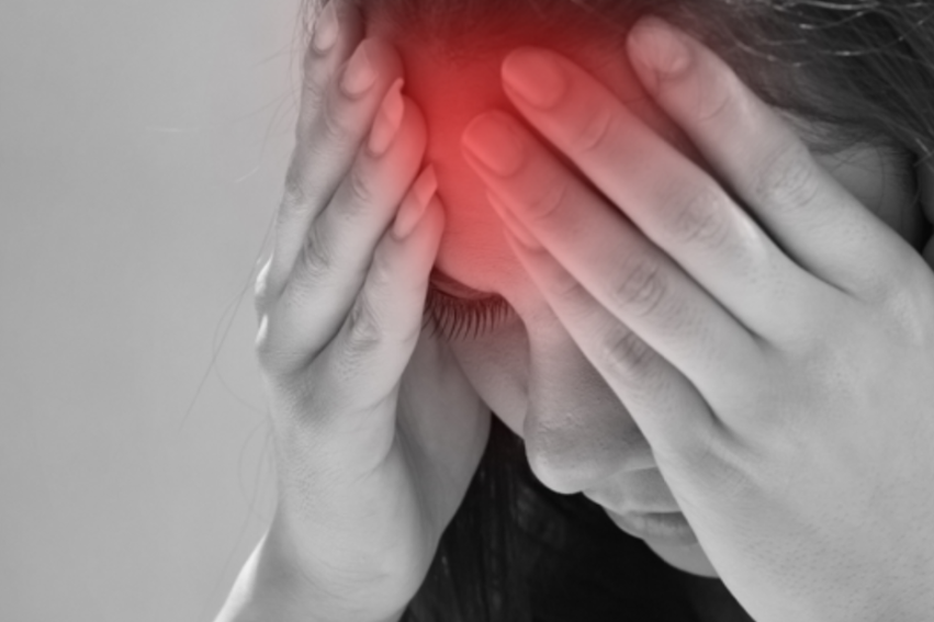 A woman in black and white experiencing a headache, which is glowing red