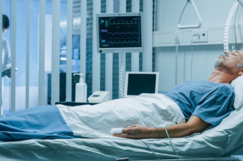 A patient lies in a hospital bed, connected to monitors