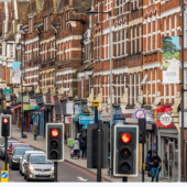 A bustling London street features a classic red double-decker bus and vibrant redbrick buildings