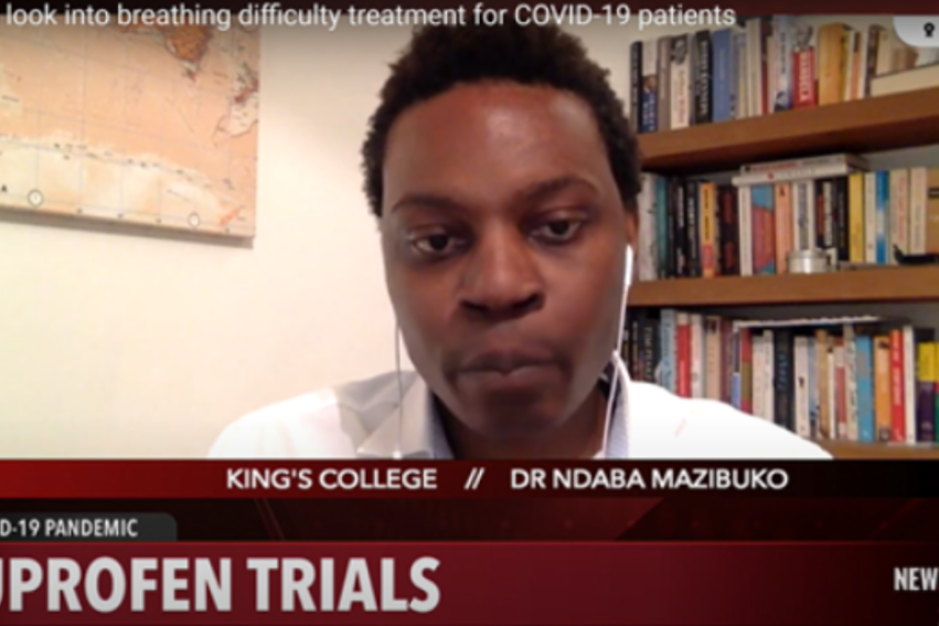A person appears on a video call discussing COVID-19 ibuprofen trials. The background has bookshelves and a map. Text includes 