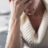 A person in a cozy sweater holds their forehead, appearing stressed or fatigued