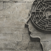 Silhouette of a human head with a maze inside against a cracked, concrete wall