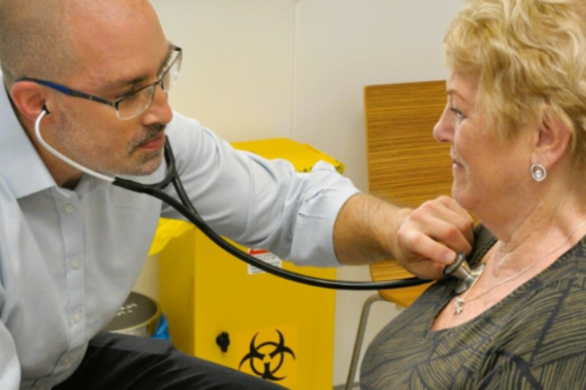 A male doctor listens to an elderly woman's heartbeat with a stethoscope in a clinic