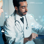 A doctor in a white coat discusses medical images on a laptop with a patient