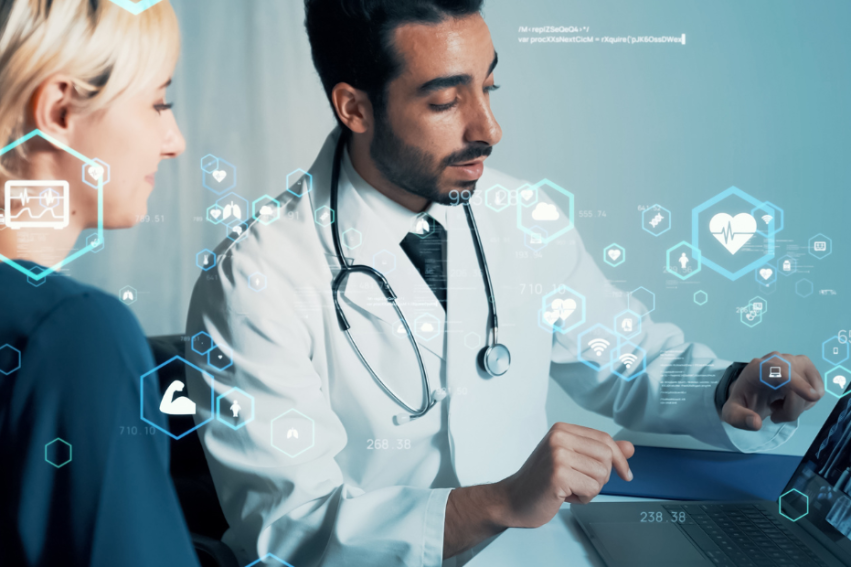 A doctor in a white coat discusses medical images on a laptop with a patient