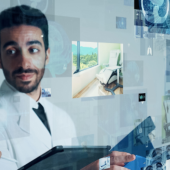 Two medical professionals in lab coats discuss while looking at futuristic digital screens displaying various medical images and data.