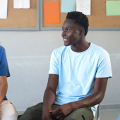 A diverse group of young adults sits in a circle, engaging in a lively discussion