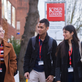 Three students walk together outside King's College London. They are wearing winter clothes