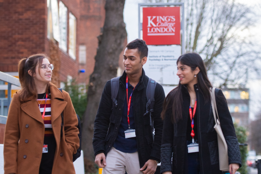 Three students walk together outside King's College London. They are wearing winter clothes