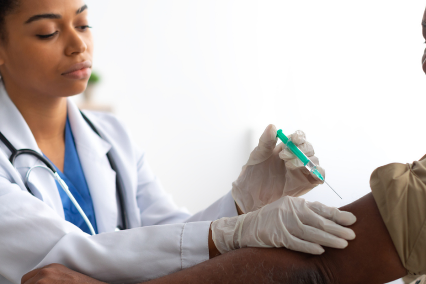 A healthcare professional in a white coat administers a vaccine to an older man.