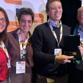 A group of six people smiling at an event with an award