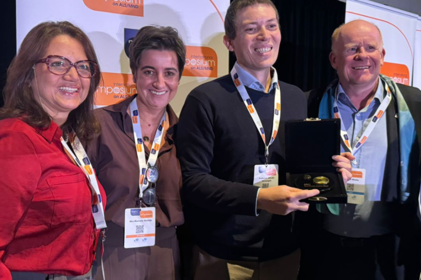 A group of six people smiling at an event with an award