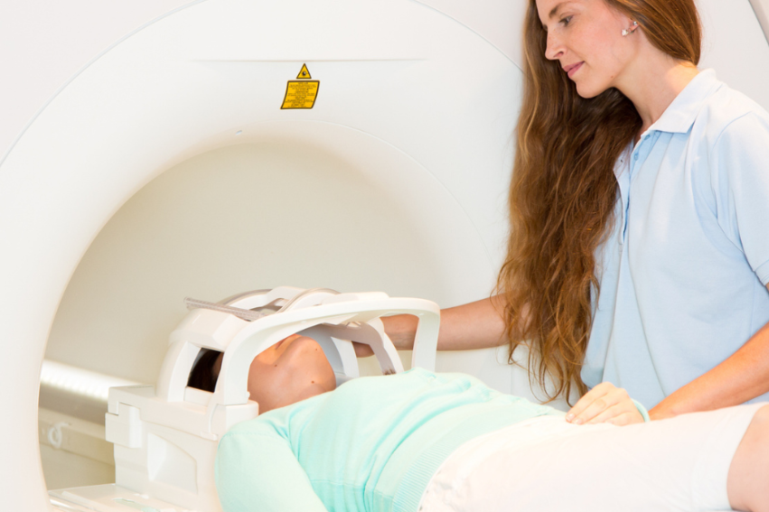 Woman operating an MRI machine with a patient lying down