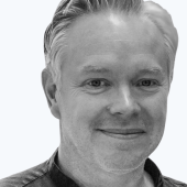 A man with short, light hair smiles warmly in a black-and-white portrait