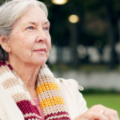 An older woman sat on a bench in a park