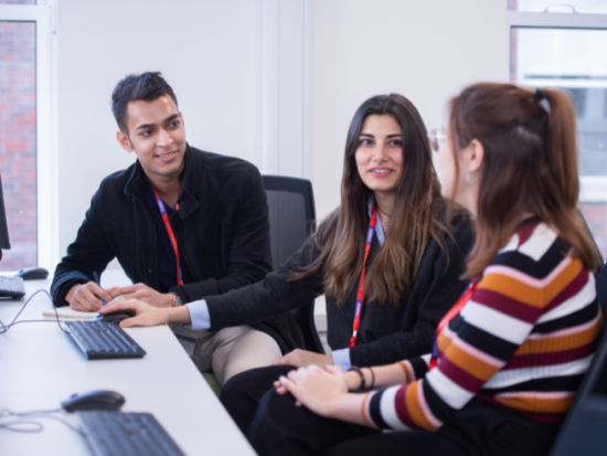 group of staff and students talking in front of a computer