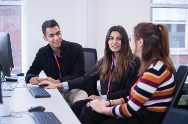 group of staff and students talking in front of a computer