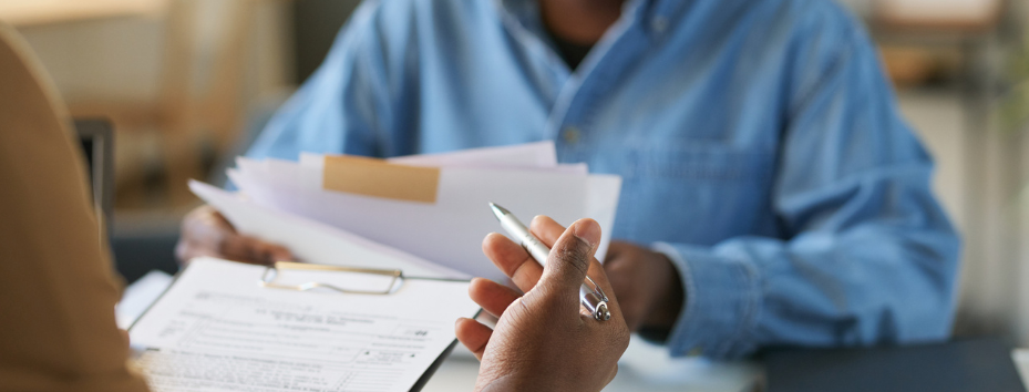 woman talking to man over a desk, pointing at papers