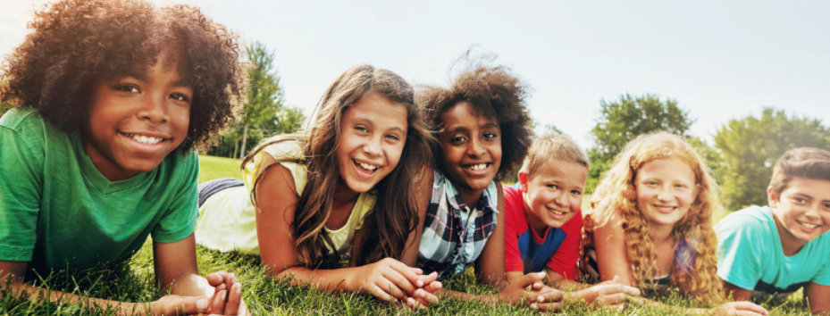children sat on grass smiling