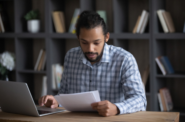 young man looking at document at laptop