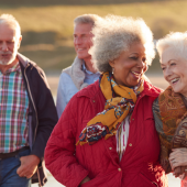 older women walk along a beach smiling