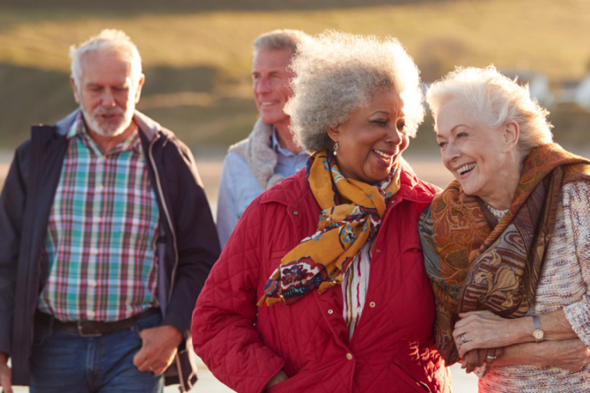 older women walk along a beach smiling