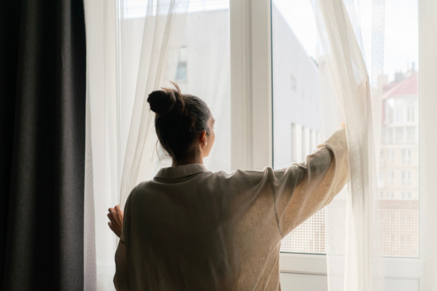Women opens curtains at a window