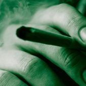 Cannabis weed, a joint in his hands A man smokes . Smoke on a black background. Concepts of medical marijuana use and legalization of the cannabis. On a black background Green Tinting stock photo